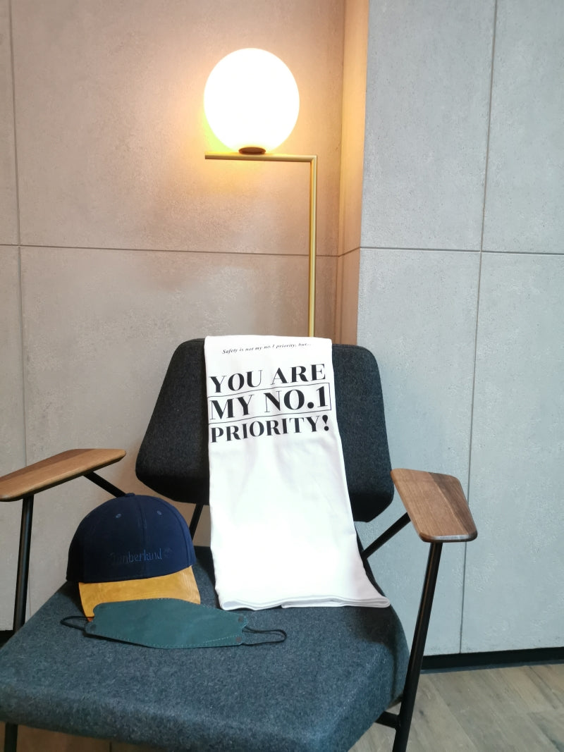 no1 priority design tshirt placing on the chair with a cap and a facemask
